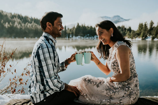 a bride and groom laugh while sharing tea in mint-colored-mugs beside a misty lake at sunrise during their Snoqualmie Washington Adventure Elopement